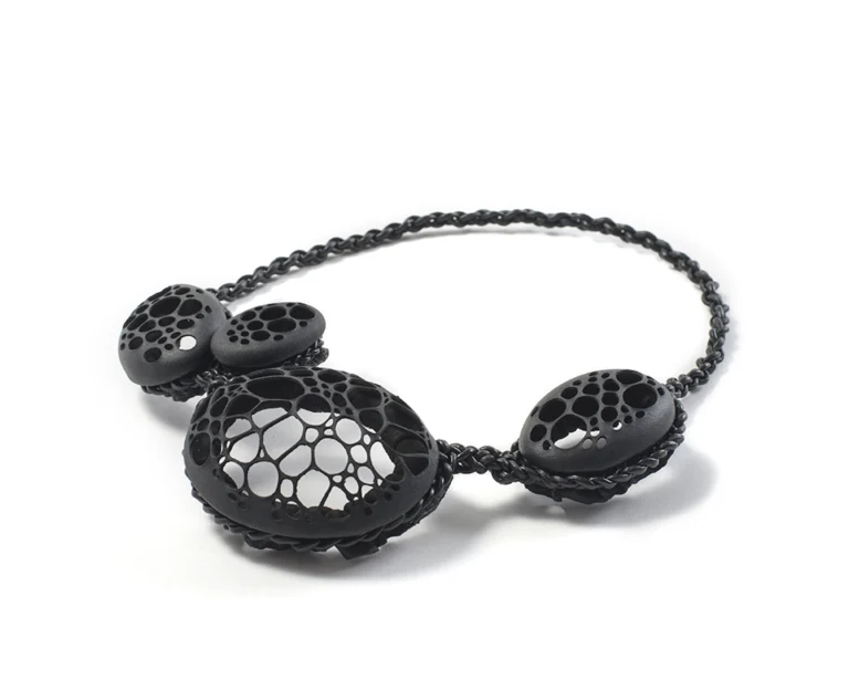 Black art jewellery leather necklace, lace pattern with circulare holes, on white background
