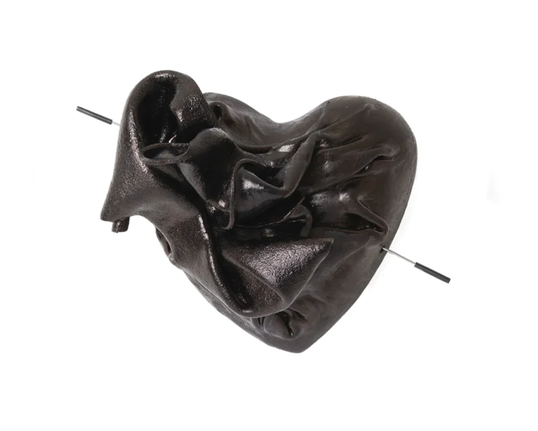 An art jewellery brooch made by wet molding naturally tanned reindeer leather into the shape of a heart. Dark maroon/purple color, with hints of brown, on white background.