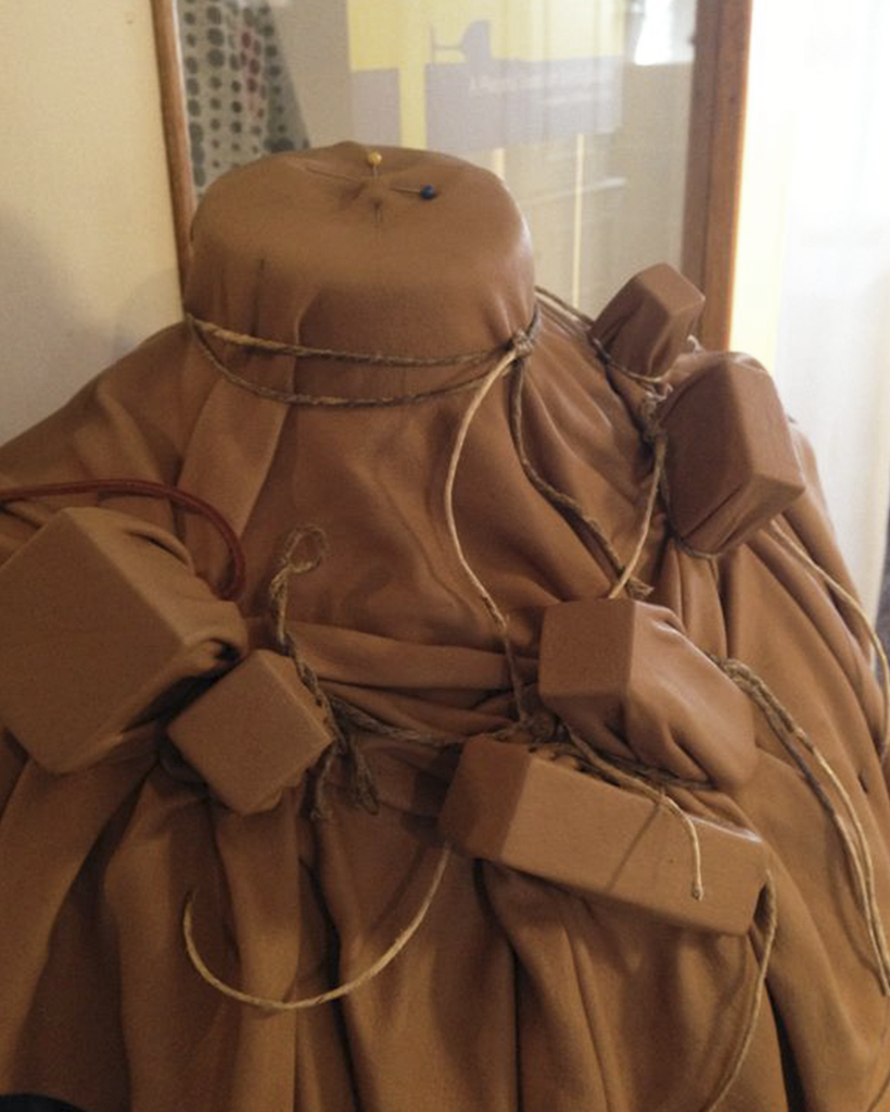 Wet leather draped over wooden blocks on a mannequin for wet molding leather.